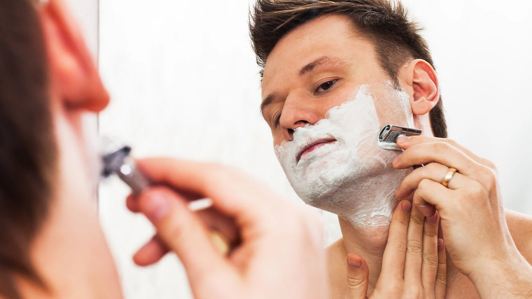 a man shaving with a metal safety razor