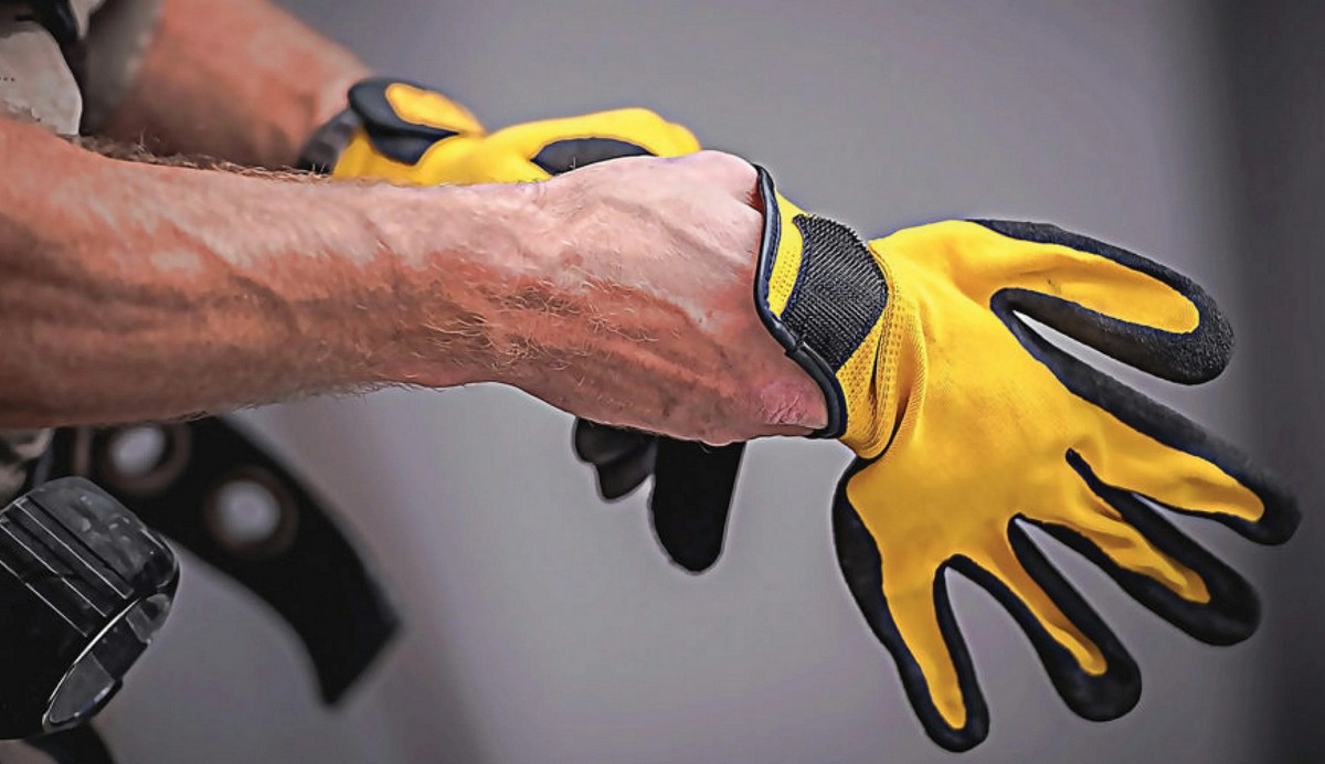 worker putting on yellow palm coated gloves